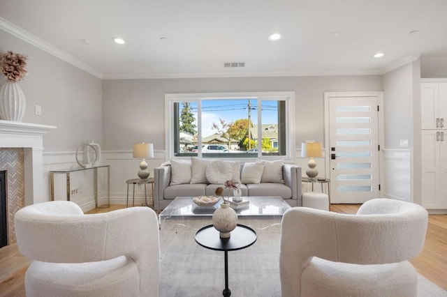 living room with crown molding, a tile fireplace, and light wood-type flooring