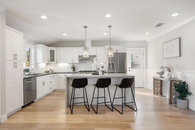 kitchen with white cabinetry, appliances with stainless steel finishes, sink, and an island with sink