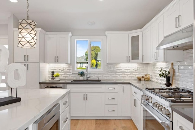 kitchen with sink, white cabinetry, hanging light fixtures, dark stone countertops, and stainless steel appliances