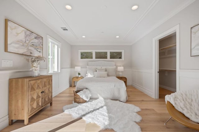 bedroom featuring ornamental molding, a spacious closet, and light hardwood / wood-style floors