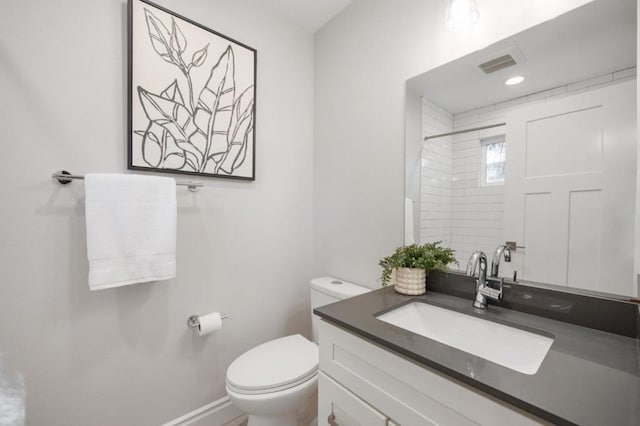 bathroom featuring vanity, toilet, and a tile shower