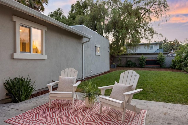 patio terrace at dusk featuring a lawn