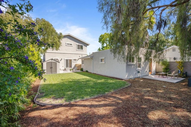 rear view of house featuring a patio, a lawn, and a storage unit