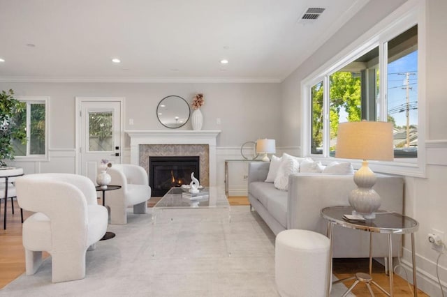 living room featuring light hardwood / wood-style flooring, crown molding, and a high end fireplace