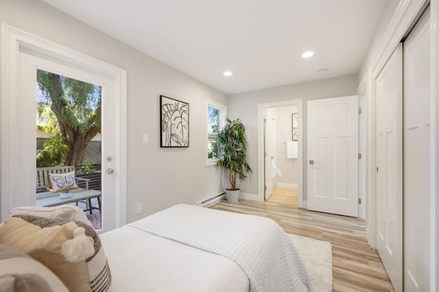 bedroom featuring ensuite bathroom, light hardwood / wood-style flooring, access to outside, baseboard heating, and a closet