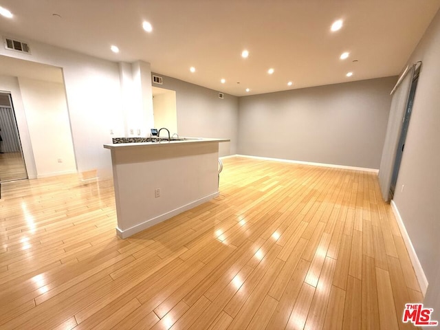 unfurnished living room featuring light wood-type flooring and sink