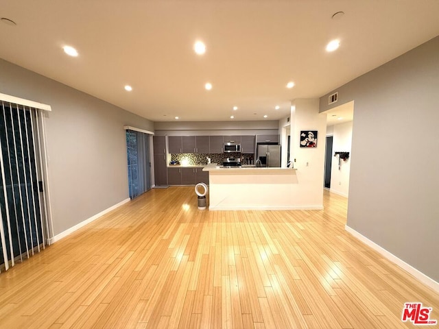 kitchen featuring tasteful backsplash, light hardwood / wood-style flooring, an island with sink, and stainless steel appliances