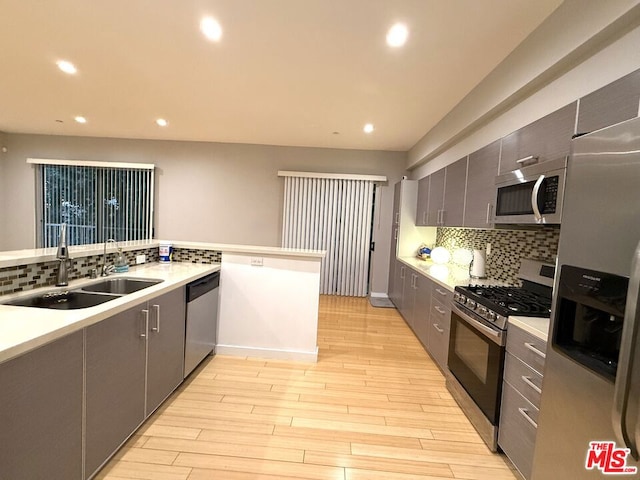 kitchen with kitchen peninsula, stainless steel appliances, light hardwood / wood-style floors, and sink