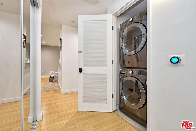 washroom with stacked washer and dryer and light hardwood / wood-style floors