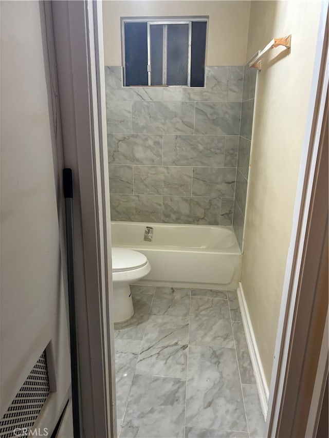 bathroom featuring tiled shower / bath, tile patterned flooring, and toilet