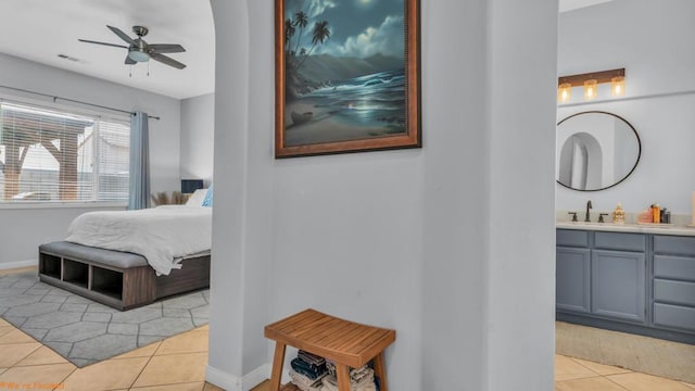 tiled bedroom with ceiling fan, sink, and connected bathroom