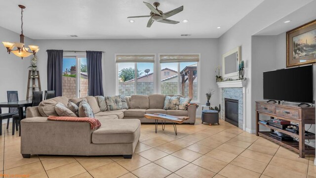 tiled living room with ceiling fan with notable chandelier and a healthy amount of sunlight