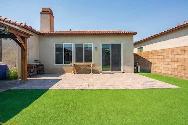 back of house featuring exterior bar, a yard, and a patio