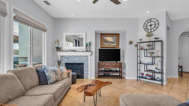 living room featuring ceiling fan, light tile patterned floors, and a fireplace