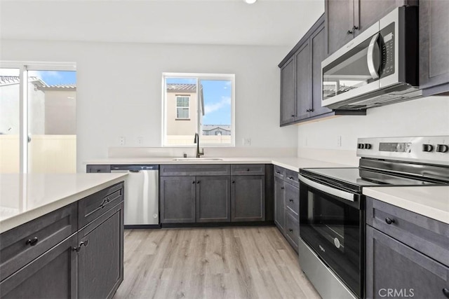 kitchen with light wood-type flooring, appliances with stainless steel finishes, and sink