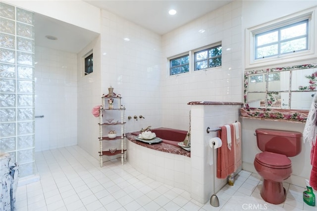 bathroom featuring tile walls, toilet, a washtub, and tile patterned flooring