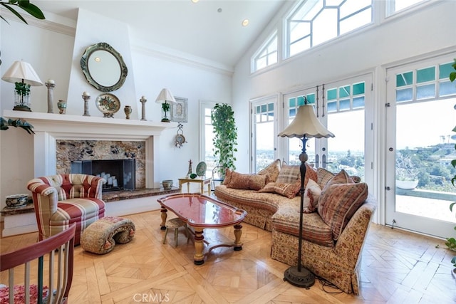 living room featuring high vaulted ceiling, a premium fireplace, light parquet flooring, and ornamental molding