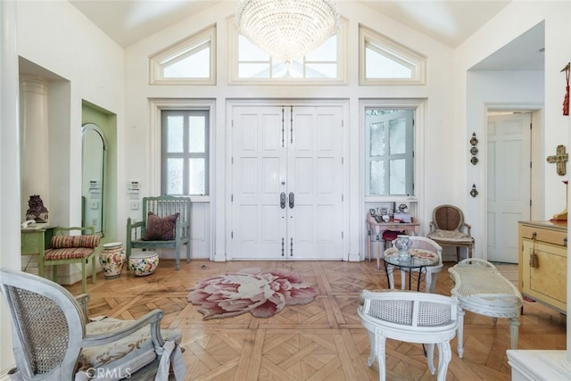 foyer featuring an inviting chandelier, light parquet flooring, and lofted ceiling