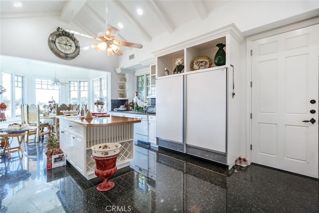 kitchen featuring lofted ceiling with beams, ceiling fan, dark tile patterned floors, white cabinetry, and a center island