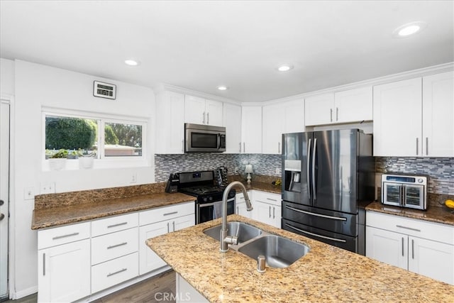 kitchen with sink, decorative backsplash, light stone countertops, and stainless steel appliances