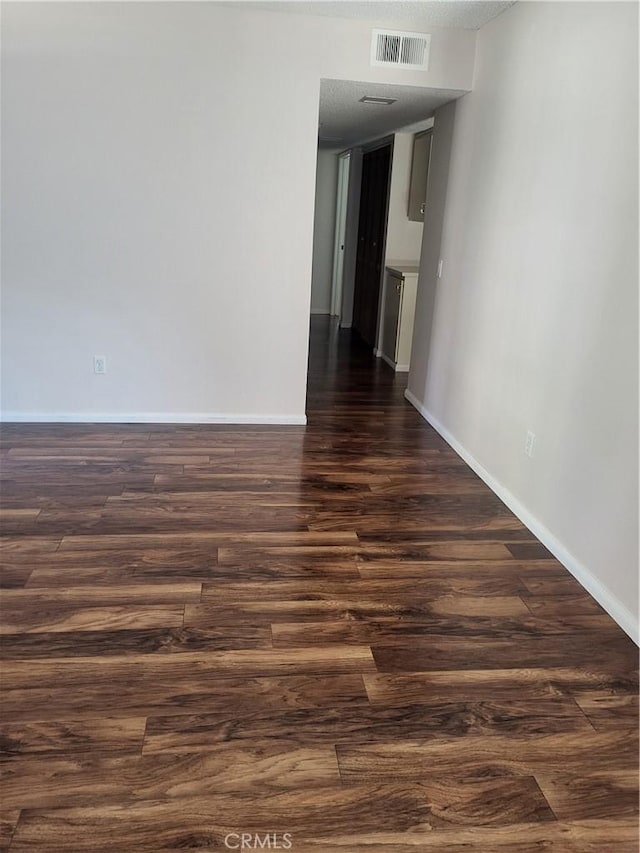 spare room featuring a textured ceiling and dark hardwood / wood-style flooring