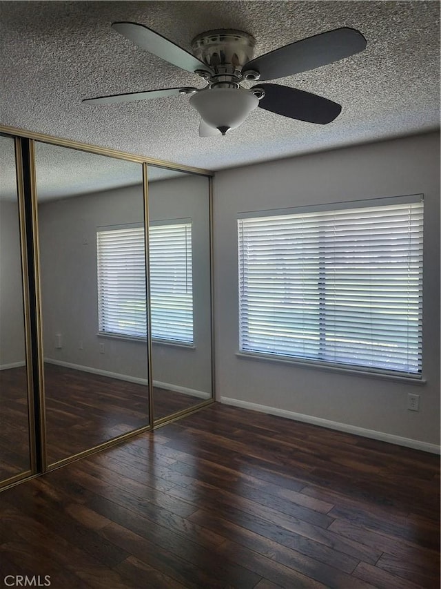 unfurnished bedroom featuring ceiling fan, dark hardwood / wood-style floors, and a closet