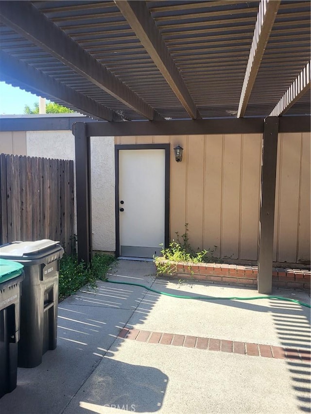 view of exterior entry with a pergola and a patio