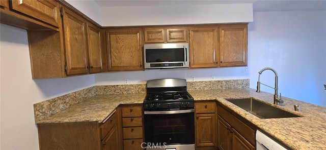 kitchen featuring dishwasher, light stone countertops, sink, and gas stove