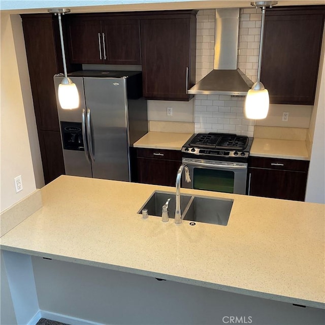 kitchen with decorative light fixtures, sink, wall chimney range hood, and stainless steel appliances