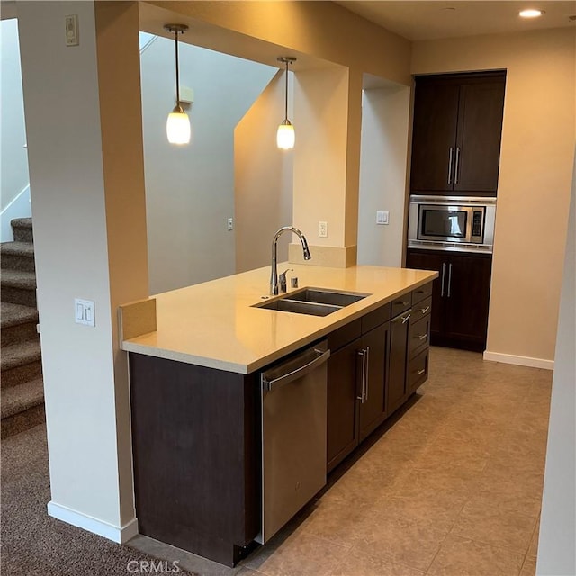 kitchen featuring hanging light fixtures, appliances with stainless steel finishes, sink, and dark brown cabinets