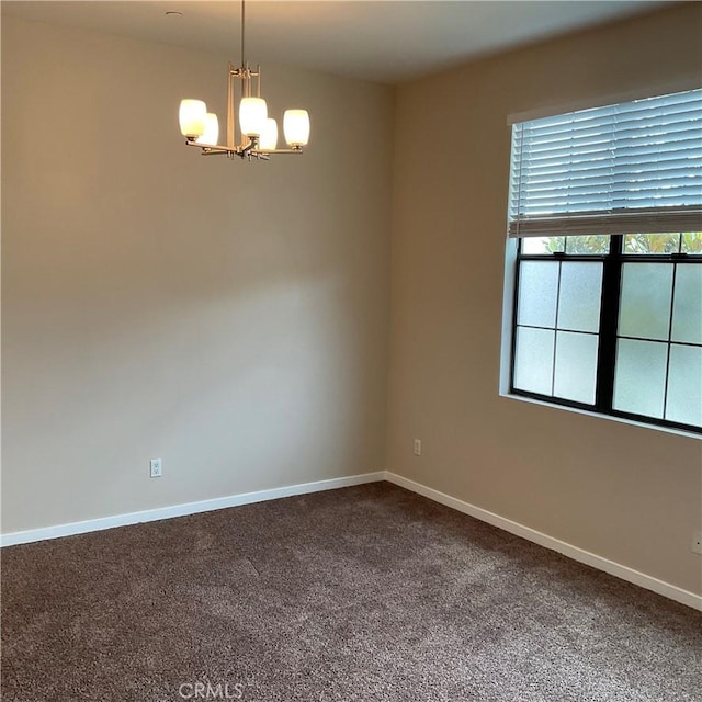 empty room with a chandelier and carpet flooring