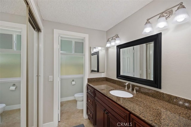 bathroom featuring toilet, a textured ceiling, tile patterned floors, and vanity