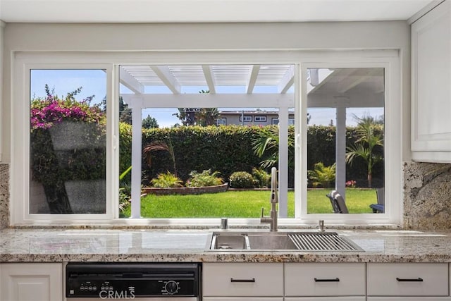 kitchen featuring backsplash, sink, white cabinetry, light stone countertops, and dishwashing machine