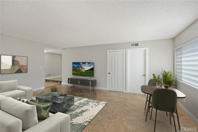 living room featuring a textured ceiling and light tile patterned floors