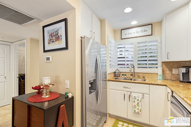 kitchen with white cabinetry, sink, decorative backsplash, light tile patterned floors, and appliances with stainless steel finishes