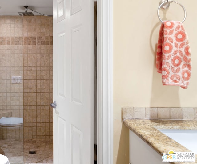 bathroom with a tile shower and vanity