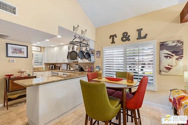 kitchen with decorative light fixtures, light tile patterned floors, white cabinetry, and stone counters