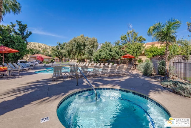 view of pool featuring a mountain view, a community hot tub, and a patio