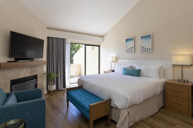 bedroom featuring a high end fireplace, vaulted ceiling, and light wood-type flooring