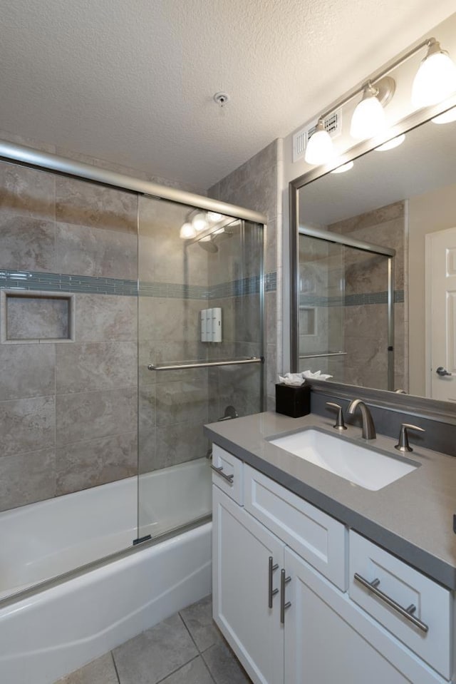 bathroom with tile patterned flooring, enclosed tub / shower combo, vanity, and a textured ceiling