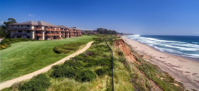 exterior space with a water view, a beach view, and a lawn