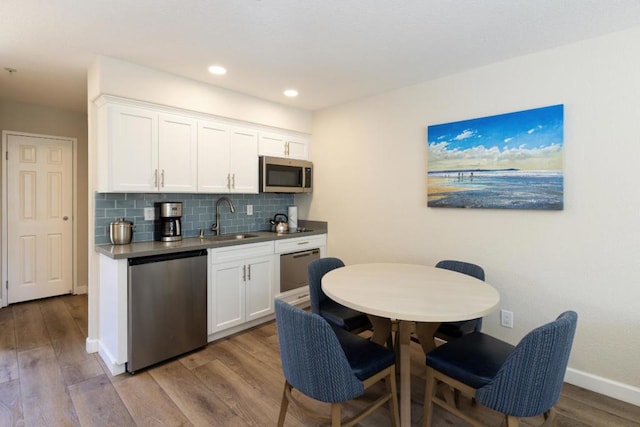 kitchen featuring tasteful backsplash, white cabinetry, sink, stainless steel appliances, and light hardwood / wood-style flooring