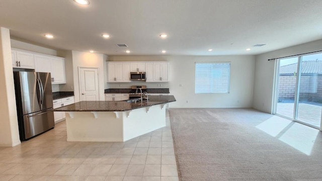 kitchen featuring white cabinets, appliances with stainless steel finishes, a breakfast bar, and a center island with sink