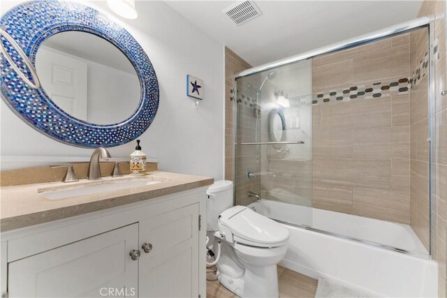 full bathroom with combined bath / shower with glass door, toilet, tile patterned floors, and vanity