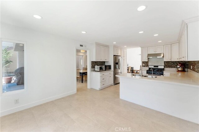 kitchen with appliances with stainless steel finishes, light tile patterned floors, white cabinets, and decorative backsplash