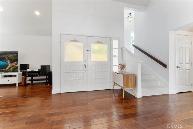 foyer entrance with wood-type flooring, french doors, and a towering ceiling