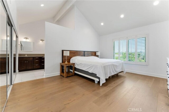 bedroom with ensuite bathroom, high vaulted ceiling, beamed ceiling, light wood-type flooring, and sink