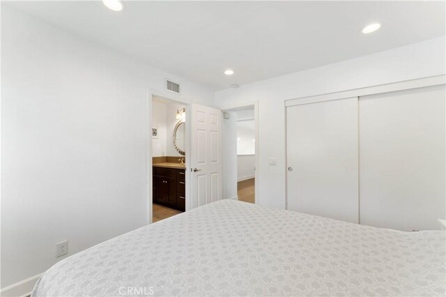 bedroom with wood-type flooring, a closet, and connected bathroom