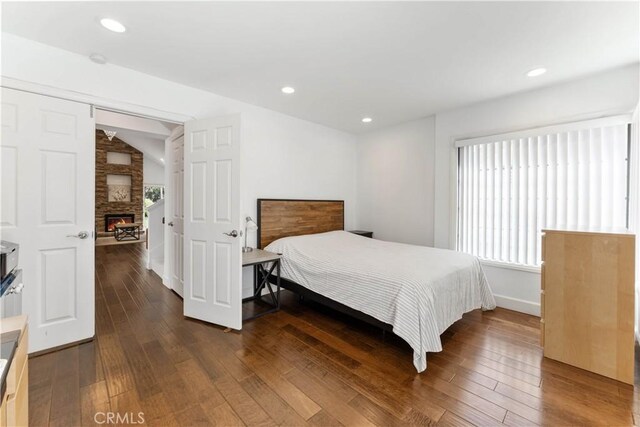 bedroom featuring a fireplace, dark wood-type flooring, and vaulted ceiling