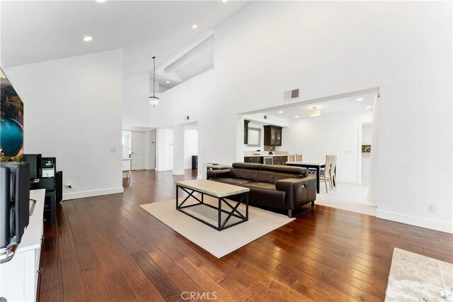 living room with a towering ceiling and dark wood-type flooring